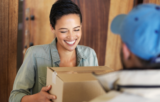 Uśmiechnięta kobieta odbierająca paczkę od kuriera